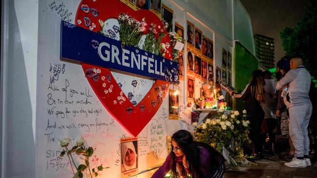 A woman lights a candle as members of the public hold a vigil and commemoration near Grenfell Tower in west London at midnight June 14, 2018 to honour the 71 people who died when a fire ripped through the Grenfell tower block in London one year ago. AFP PHOTO / Tolga Akmen