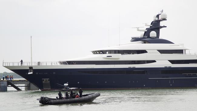 FILE - In this Aug. 7, 2018, file photo, Malaysia's marine police on their security boat watch luxury yacht Equanimity, allegedly bought with money stolen from the multibillion-dollar looting of a state investment fund, arriving at Port Klang in Klang, Malaysia. Malaysia's government launched a one-month auction for the luxury yacht bought with money stolen from the multibillion-dollar looting of a state investment fund. The sale that began Monday, Oct. 29, 2018, came nearly three months after Indonesia returned the $250 million yacht after seizing it off Bali in February in cooperation with the U.S. FBI. (AP Photo/Yam G-Jun, File)