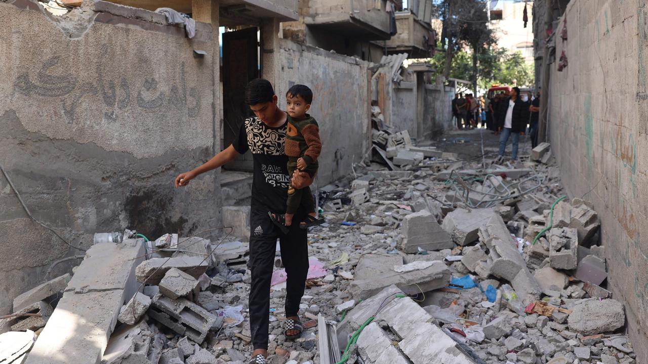 Palestinian youth carries a child as he walks through the rubble following Israeli bombardment of Rafah's Tal al-Sultan district in the southern Gaza Strip on May 7, 2024. Picture: AFP