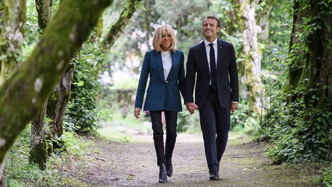 French President Emmanuel Macron walks with his wife Brigitte Macron in the park of the newly restored Chateau de Ferney-Voltaire, in Ferney-Voltaire, eastern France, on May 31, 2018.  / AFP PHOTO / Fabrice COFFRINI