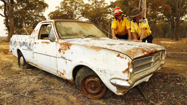 RFS members from the Illawarra Strike Force Team pictured surveying a map on the bonnet of an old car. Picture: Sam Ruttyn