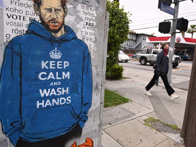 People walk past graffiti of Prince Harry wearing a hoodie reading "Keep Calm and Wash Your Hands," in Los Angeles, California. Picture: AFP