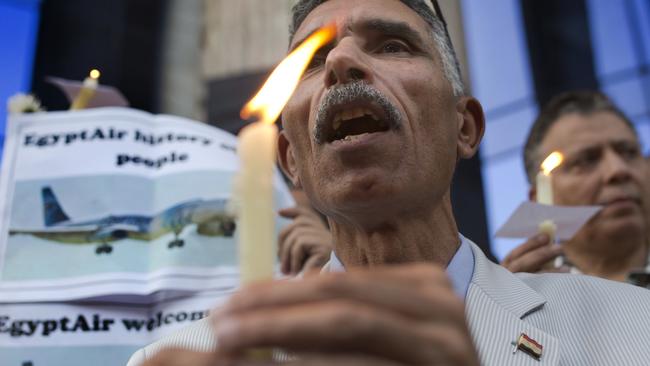 An Egyptian journalist holds a candle and a poster supporting EgyptAir victims during a candlelight vigil in Cairo on Tuesday. Picture: AP/Amr Nabil