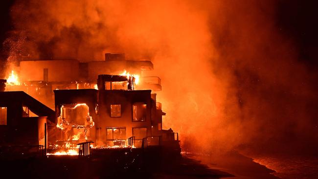 TOPSHOT - A beach house is engulfed in flames as the Palisades Fire burns along Pacific Coast Highway in Malibu, California, on January 8, 2025. At least five people have been killed in wildfires rampaging around Los Angeles, officials said on January 8, with firefighters overwhelmed by the speed and ferocity of multiple blazes -- including in Hollywood. (Photo by AGUSTIN PAULLIER / AFP)