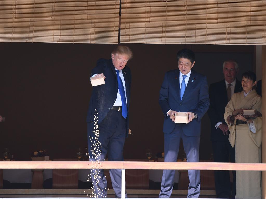 US President Donald Trump feeding koi fish as Japanese Prime Minister Shinzo Abe looks on during a welcoming ceremony in Tokyo. Picture: AFP