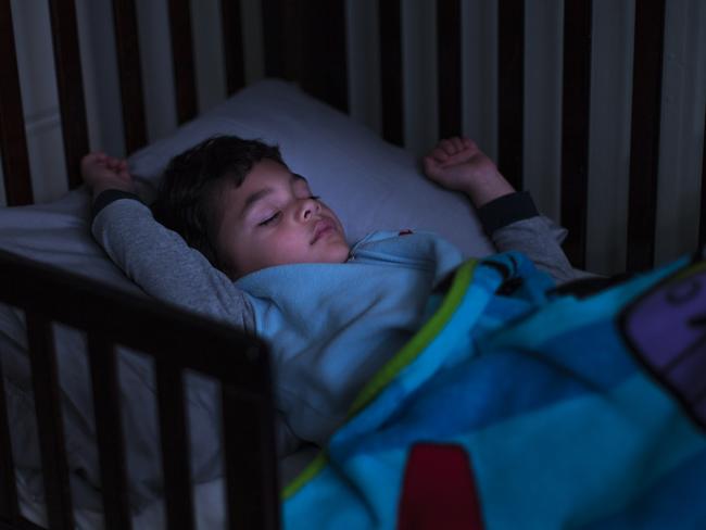 Stock photo of a young handsome boy sleeping in a bed with light on his face. Picture:iStock