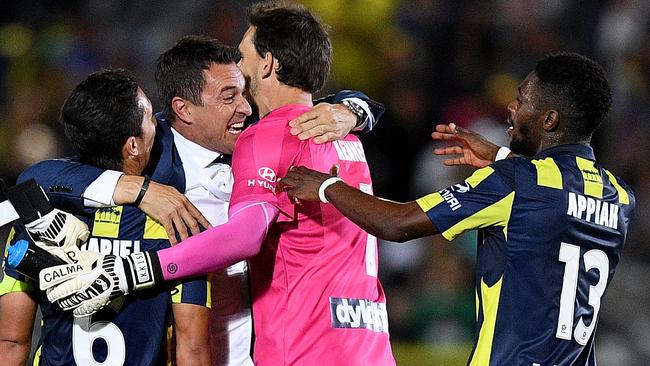 Mariners coach Paul Okon celebrates with Tom Hiariej (left) Ben Kennedy and Kwabena Appiah-Kubi after their win over Sydney FC.