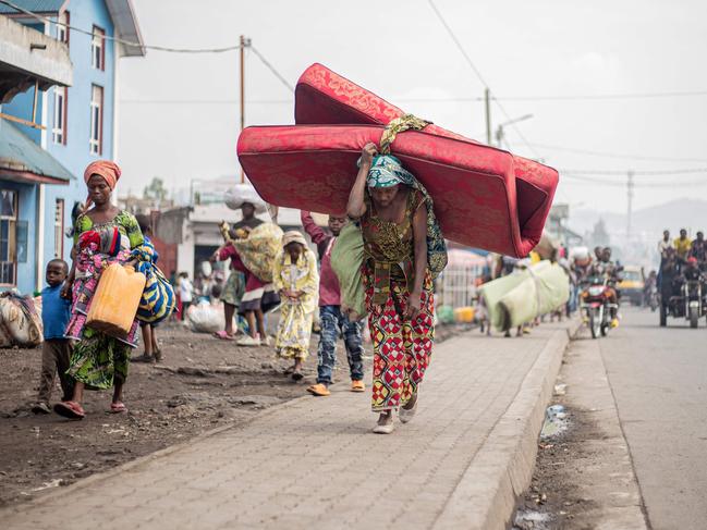 A woman carries a mattress and other belongings on her head as she flees from Kibati, where fighting has intensified, towards the city of Goma on January 26, 2025. The M23 armed group has seized further territory in the east of the Democratic Republic of Congo and on Sunday was continuing to tighten its grip on provincial capital Goma, which is almost surrounded by fighting. (Photo by Jospin Mwisha / AFP)