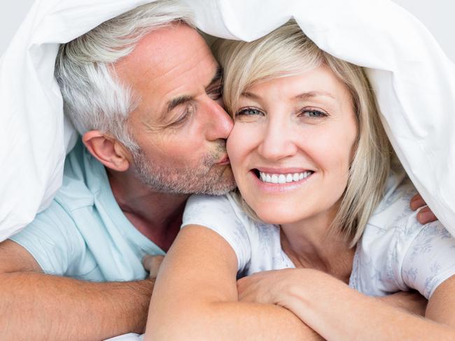 Closeup of a mature man kissing womans cheek in bed at the home