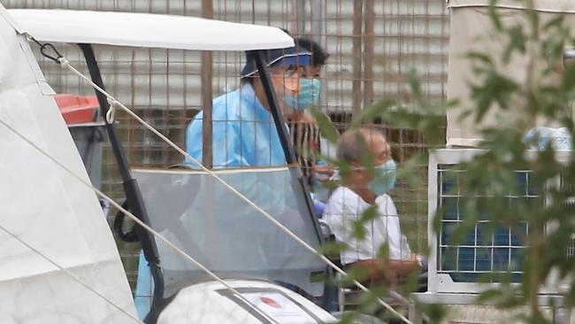 A 78-year-old Australian evacuee, who tested positive to coronavirus, and his wife are taken from the Howard Springs quarantine camp to a waiting ambulance. The couple are being flown to their home state of Western Australia. Picture: Glenn Campbell