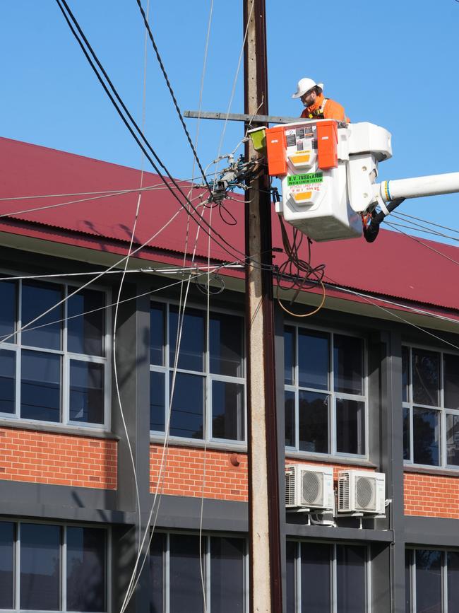 Linesmen are repairing high voltage lines that have cut power and damaged the school campus. Picture: Dean Martin