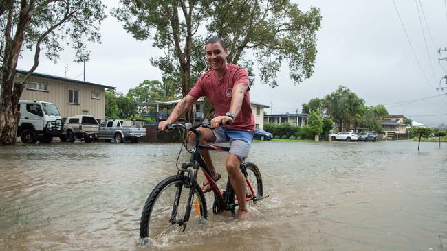 Maroochydore resident Jamie Moore rides to the shops as the Maroochy River rises. Picture: Brad Fleet