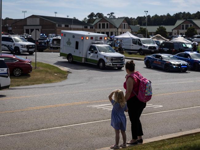 A woman and her daughter watch on as police and emergency services surround Apalachee High School where four people died. Picture: AFP