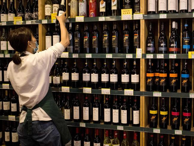 An employee works as Australian-made wine (on display shelves on R) are seen for sale at a store in Beijing on August 18, 2020. - China on August 18 ramped up tensions with Australia after it launched a probe into wine imports from the country, the latest salvo in an increasingly bitter row between the trade partners. (Photo by NOEL CELIS / AFP)