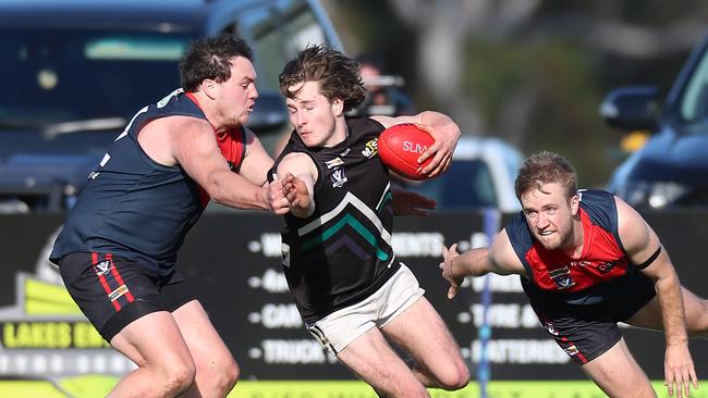 Omeo-Benambra’s William Cook takes on two Swifts Creek opponents. Picture Yuri Kouzmin