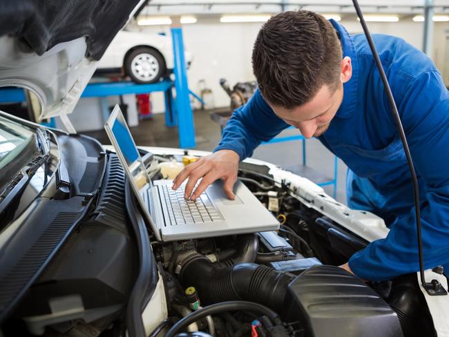 Generic mechanic using laptop on car at the repair garage. Townsville