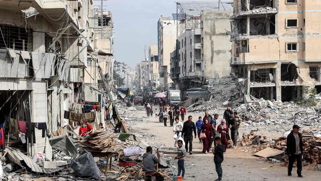 People walk past the rubble of collapsed and damaged buildings along a street in Gaza City. Picture: AFP.