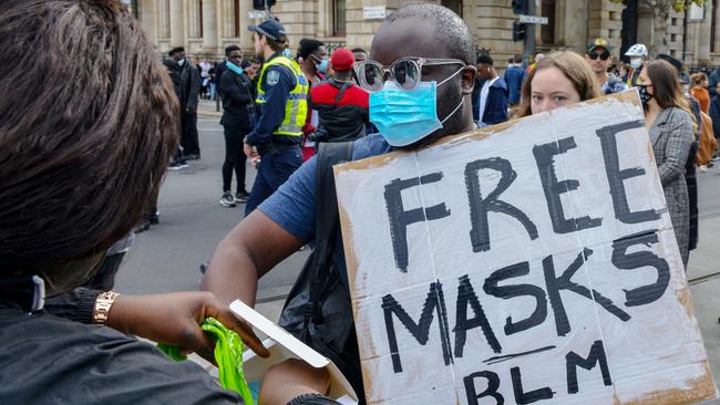 Peter Madida hands out face masks at the rally. Picture: Brenton Edwards