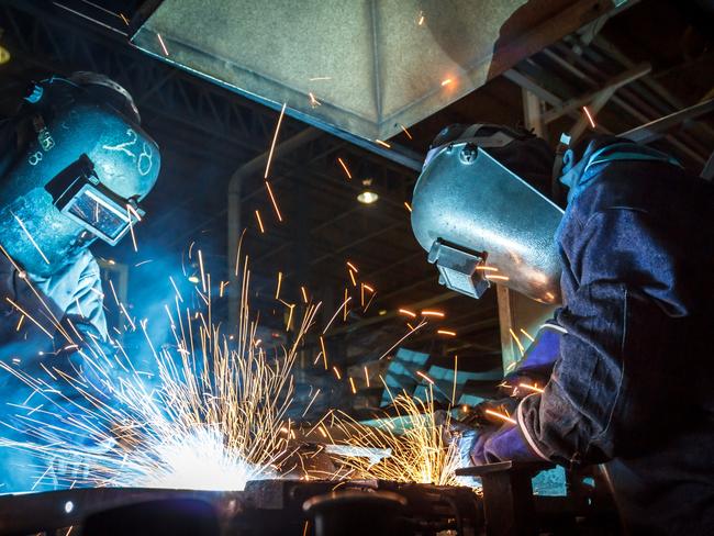 The movement of workers with protective mask welding metal. Australian manufacturing workers generic, blue collar