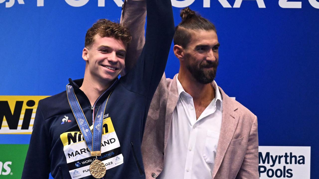 (L-R) Gold medallist France's Leon Marchand celebrates with former US swimmer Michael Phelps during the medals ceremony for men's 400m medley swimming event during the World Aquatics Championships in Fukuoka on July 23, 2023. (Photo by MANAN VATSYAYANA / AFP)