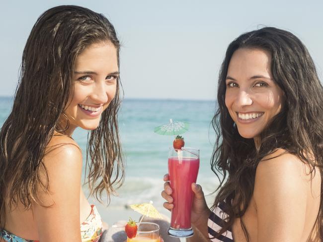 Two women having cocktails on the beach. Picture: iStock