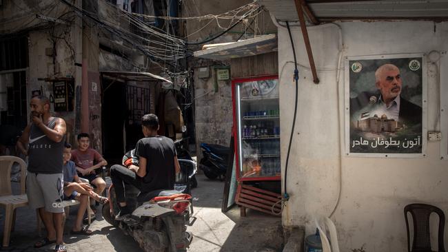 People sit next to a poster of newly appointed Hamas leader Yahya Sinwar in the Palestinian camp of Bourj al-Barajneh in Beirut. Picture: Chris McGrath/Getty Images