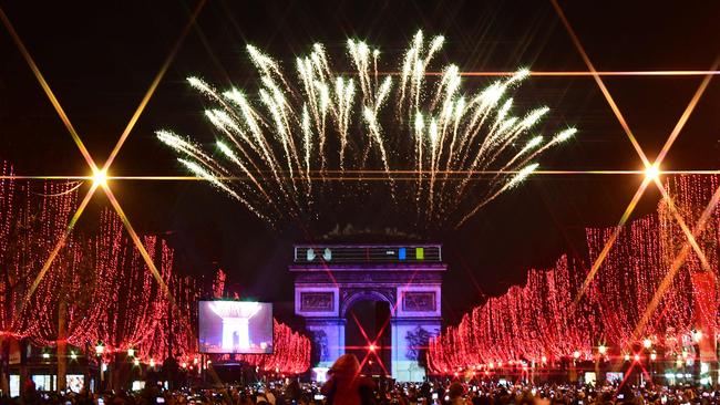 People take pictures of the fireworks erupting in the sky over the Arc de Triomphe. Picture: Martin Bureau/AFP