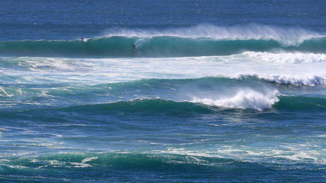 A surfer enjoy the continuing great swell on the Gold Coast with massive waves breakiing in front of the Tweed River mouth off Duranbah Beach. Pics Adam Head