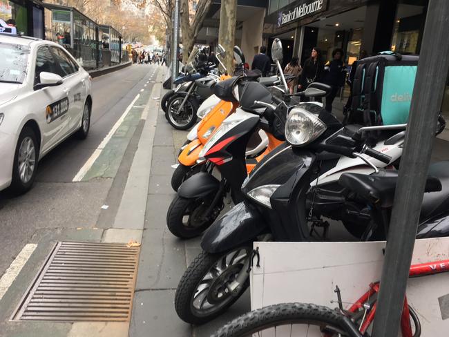 Motorcycles and scooters lined up on Collins St in Melbourne's CBD.