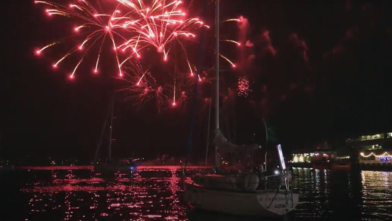 The final yacht in the Sydney to Hobart yacht race Currawong heads back to the docks as the fireworks light up the Hobart sky.