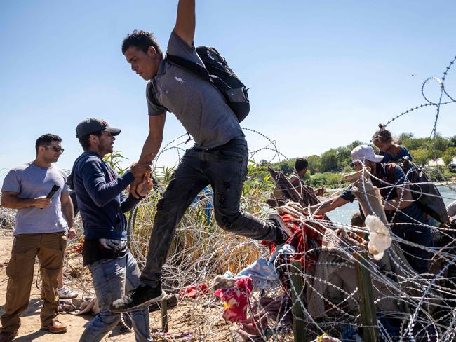 EAGLE PASS, TEXAS - SEPTEMBER 28: Immigrants cross over razor wire after crossing from Mexico into the United States on September 28, 2023 in Eagle Pass, Texas. A surge of asylum seeking migrants crossing the U.S. southern border has put pressure on U.S. immigration authorities, reaching record levels in recent weeks.   John Moore/Getty Images/AFP (Photo by JOHN MOORE / GETTY IMAGES NORTH AMERICA / Getty Images via AFP)