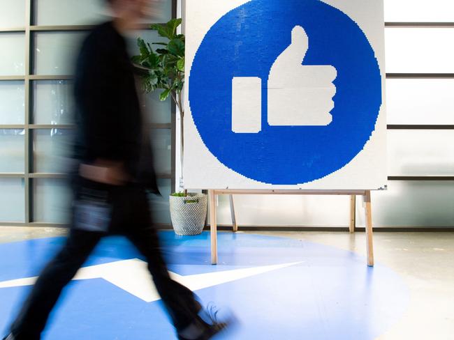 (FILES) This file photo taken on October 23, 2019 shows a Facebook employee walking past a sign displaying the "like" sign at Facebook's corporate headquarters campus in Menlo Park, California. - Facebook was branded "arrogant" and "unconscionable" for banning Australian users from sharing news on February 18, 2021, as its defiant response to government regulation inadvertently crippled the pages of several emergency services. (Photo by Josh Edelson / AFP)