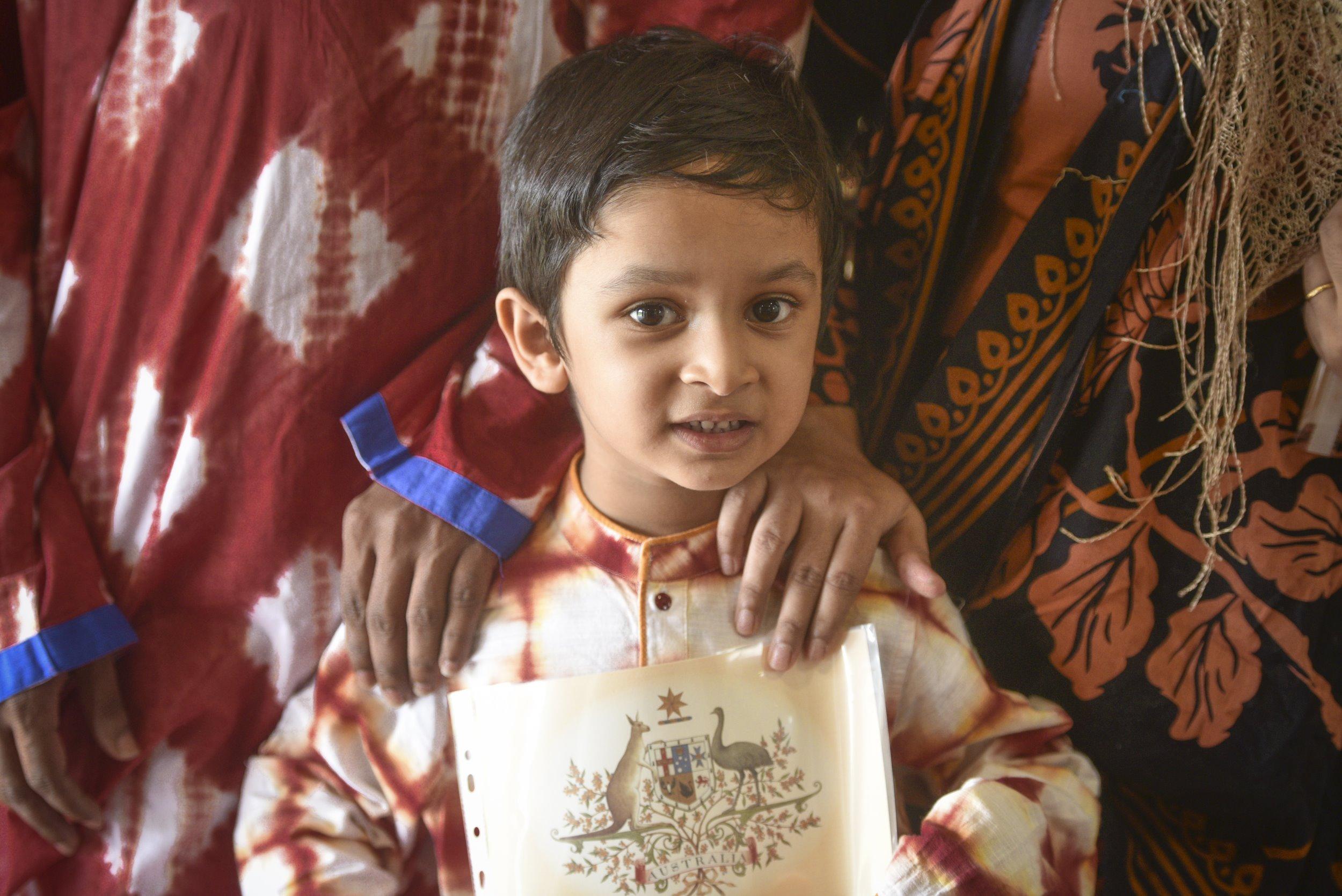 Muhammad Hasan shows off his citizenship certificate with a hand from his parents on his shoulder at the citizenship ceremony at Ellem Oval. Picture: Adam Hourigan