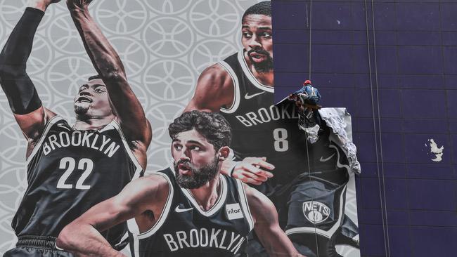 A worker removes from a building a promotional banner NBA preseason game between the Brooklyn Nets and the Los Angeles Lakers in Shanghai. Picture: AFP