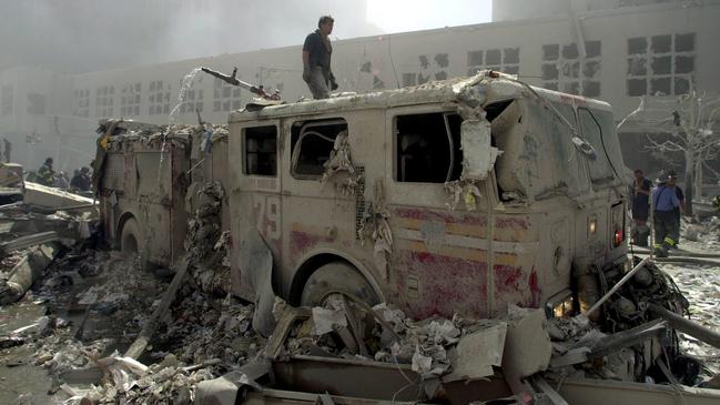 Pictures from ground zero after the September 11 terror attacks on the World Trade Centre. A firefighter stands on a destroyed truck from Engine 279 in Red Hook New York. Picture: Nathan Edwards