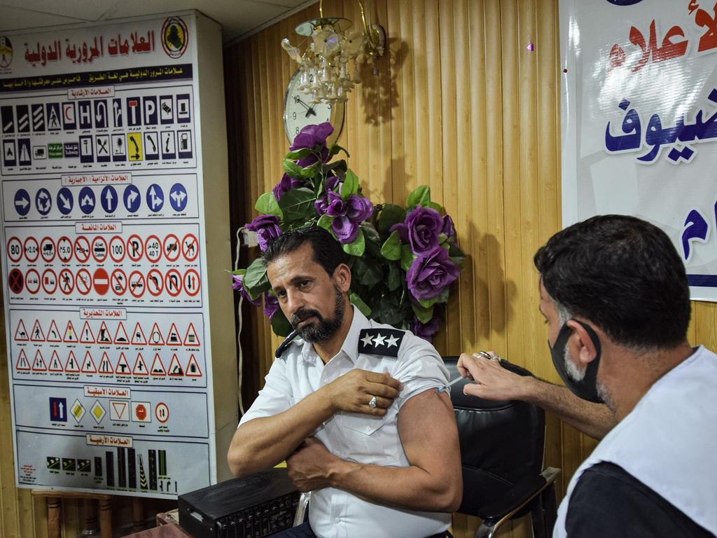 A medic administers a dose of the Pfizer-BioNTech COVID-19 coronavirus vaccine to a policeman during a health department vaccination campaign in Iraq's southern city of Nasiriyah on July 28, 2021. (Photo by Asaad NIAZI / AFP)