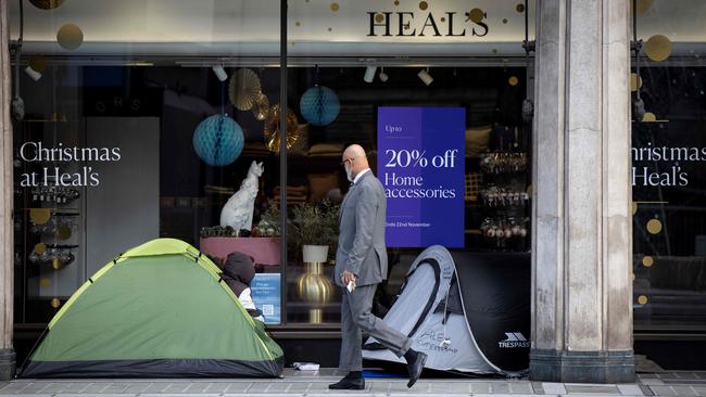 A pedestrian walks past the tents of homeless people outside a shop displaying Christmas-themed window displays in London. Picture: AFP