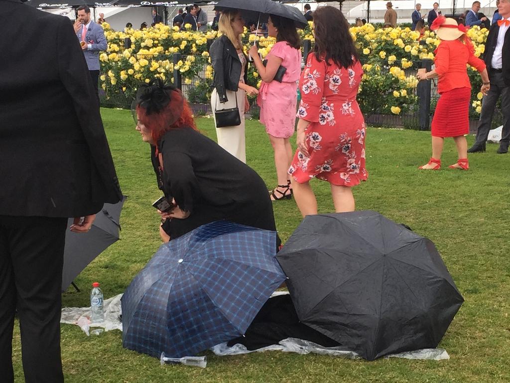 As the weather clears, a woman emerges from her umbrella cave.