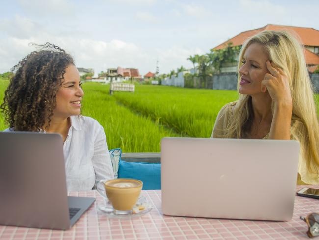 two happy female friends working outdoors at beautiful internet cafe with laptop computer , a caucasian woman and an afro mixed ethnicity girl enjoying together as digital nomad girlfriends. Drinking coffee, Digital Nomad, Freelancer, Bali, Picture - Istock