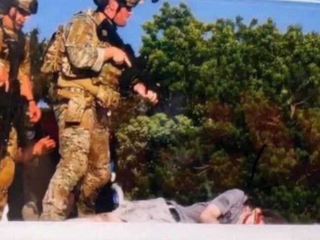 Law enforcement officers stand over the body of the shooter.