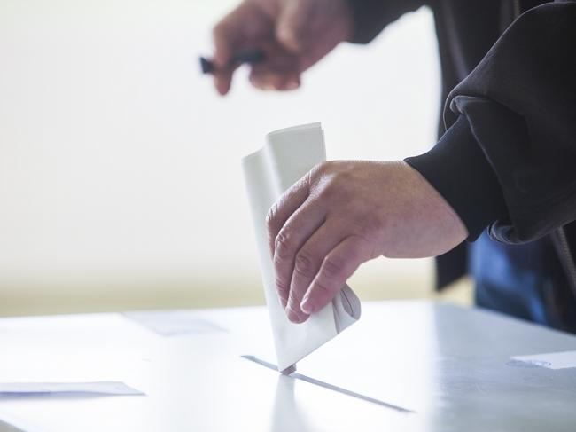 Hand of a person casting a ballot at a polling station during voting. election voting vote polling poll generic Townsville