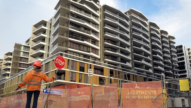 This photo taken on June 17, 2016 shows a worker holding a stop sign in front of an apartment block under construction in Sydney. Sydney is imposing new taxes on foreigners buying homes amid growing concerns that a flood of mostly Chinese investors is crowding out locals and killing the "Great Australian Dream" of owning property. / AFP PHOTO / WILLIAM WEST / TO GO WITH Australia-China-property-tax,FOCUS by Glenda KWEK