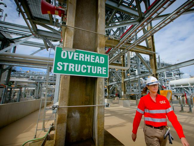 A worker walks past a sign reading "Overhead Structure" at the Queensland Curtis Liquefied Natural Gas (QCLNG) project site, operated by QGC Pty, a unit of Royal Dutch Shell Plc, in Gladstone, Australia, on Wednesday, June 15, 2016. Gas from more than 2,500 wells travels hundreds of miles by pipeline to the project, where it's chilled and pumped into 10-story-high tanks before being loaded onto massive ships. Photographer: Patrick Hamilton/Bloomberg