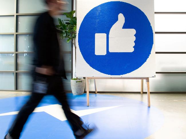 (FILES) This file photo taken on October 23, 2019 shows a Facebook employee walking past a sign displaying the "like" sign at Facebook's corporate headquarters campus in Menlo Park, California. - Facebook was branded "arrogant" and "unconscionable" for banning Australian users from sharing news on February 18, 2021, as its defiant response to government regulation inadvertently crippled the pages of several emergency services. (Photo by Josh Edelson / AFP)