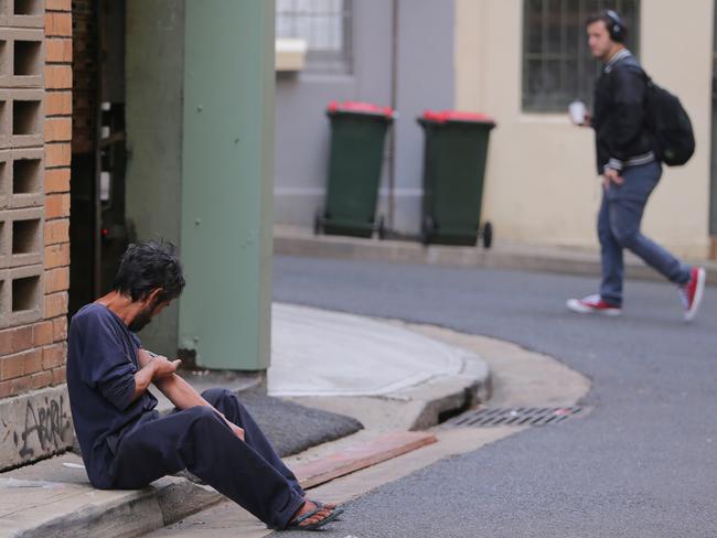 Oblivious to passers-by, the man injects himself in the gutter. Picture: John Grainger