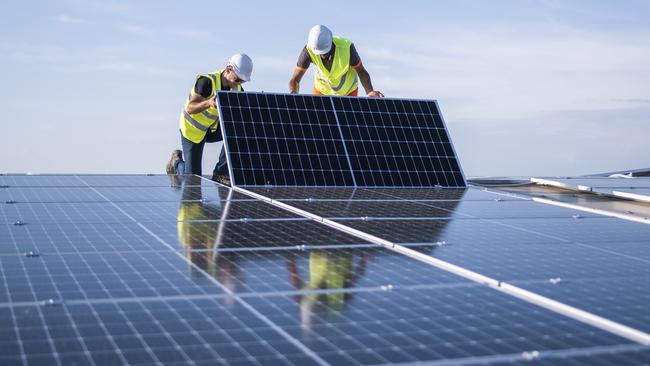 Team of two engineers installing solar panels on industrial factory roof.