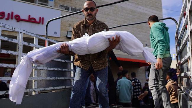 A Palestinian man carries a shrouded body, killed in overnight Israeli bombardment, ahead of a funeral at Al-Aqsa Martyrs Hospital in Deir al-Balah. Picture: AFP