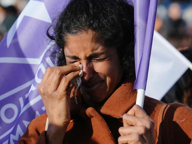 A woman sheds tears as she holds a flag of the "Fondation des Femmes" women's rights group as people gather at the Place du Trocadero in Paris, on March 4, 2024, during the broadcasting of the convocation of both houses of parliament to anchor the right of abortion in the country's constitution. If congress approves the move, France will become the only country in the world to clearly protect the right to terminate a pregnancy in its basic law. (Photo by Dimitar DILKOFF / AFP)