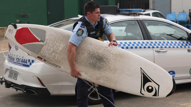 Police recover the surfboard belonging to the surfer who was taken unconscious from the surf at Collaroy Beach today. Picture John Grainger