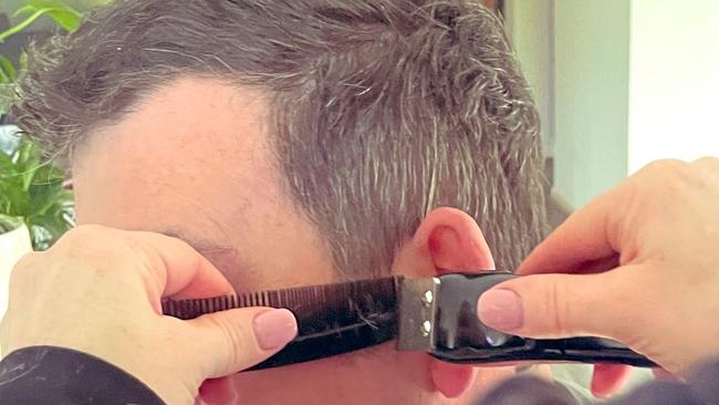 Daniel Andrews gets a home haircut from wife Cath.